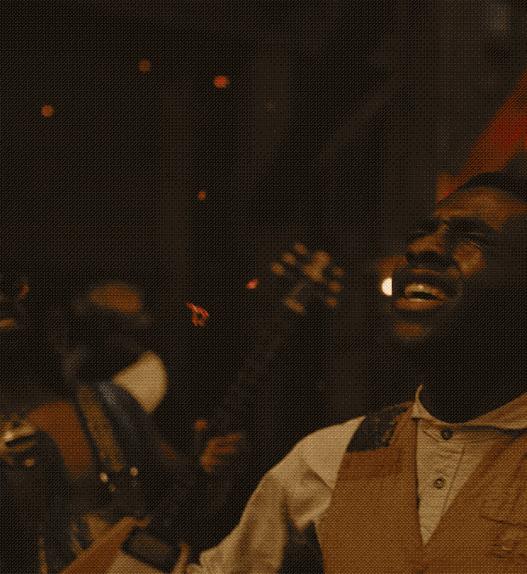 a screenshot of a film showing a man in the middle of passionately singing