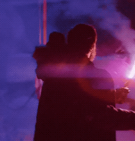 a man in winter gear in the snow at night, facing away from the camera, holding an emergency flare