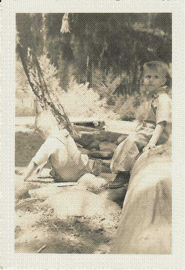 black and white photo of two toddler-aged boys in overalls sitting on rocks in an outdoor area
