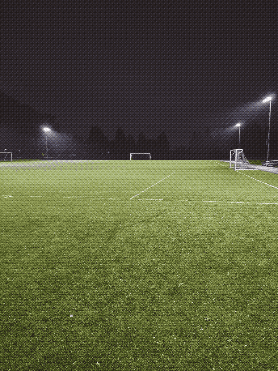 a brightly lit, empty soccer field in the middle of the night