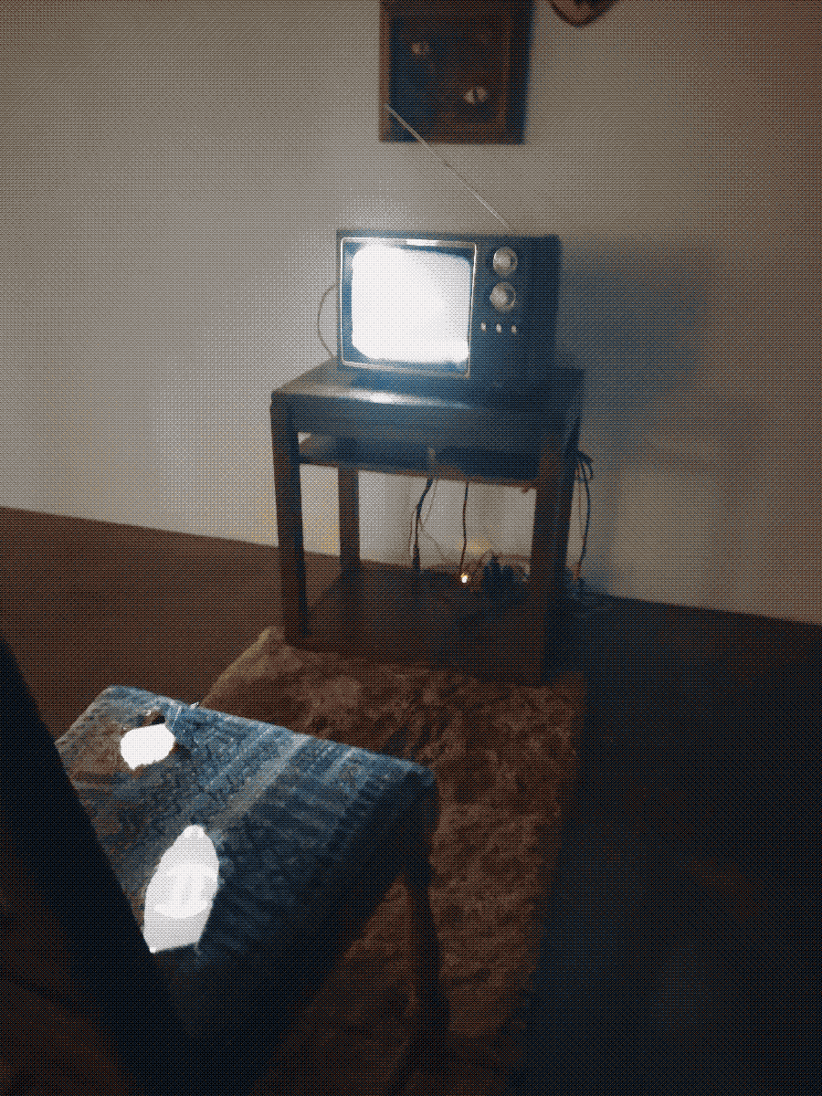 a torn chair facing a small cable tv tuned to static in an unoccupied room